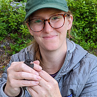 Dr. Allyson Jackson holding a bird during field work