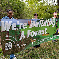 Students holding a banner that reads We're building a forest