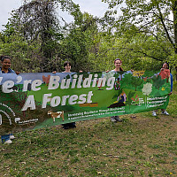 Ashlee (far right) and other interns holding a banner for the new Commons Experimental Forest