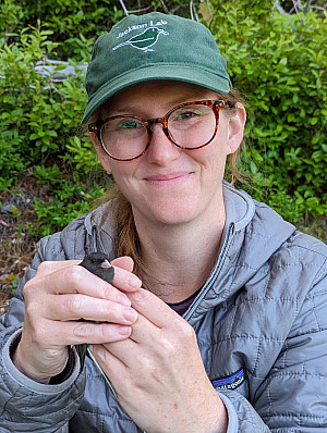Dr. Allyson Jackson holding a bird during field work
