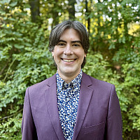 Dr. Galloway standing before a verdant wooded background.