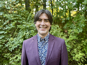 Dr. Galloway standing before a verdant wooded background.