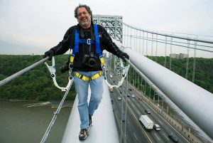 David Handschuh stands on a bridge with belt straps attached to the railings
