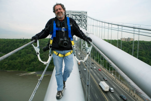 David Handschuh stands on a bridge with belt straps attached to the railings