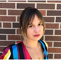 Ameila Gramling wearing multi-colored striped top standing against brick wall