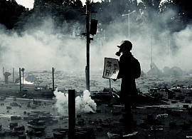 Man in  gas mask holding sign that says End