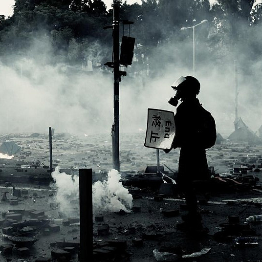 Man in  gas mask holding sign that says End