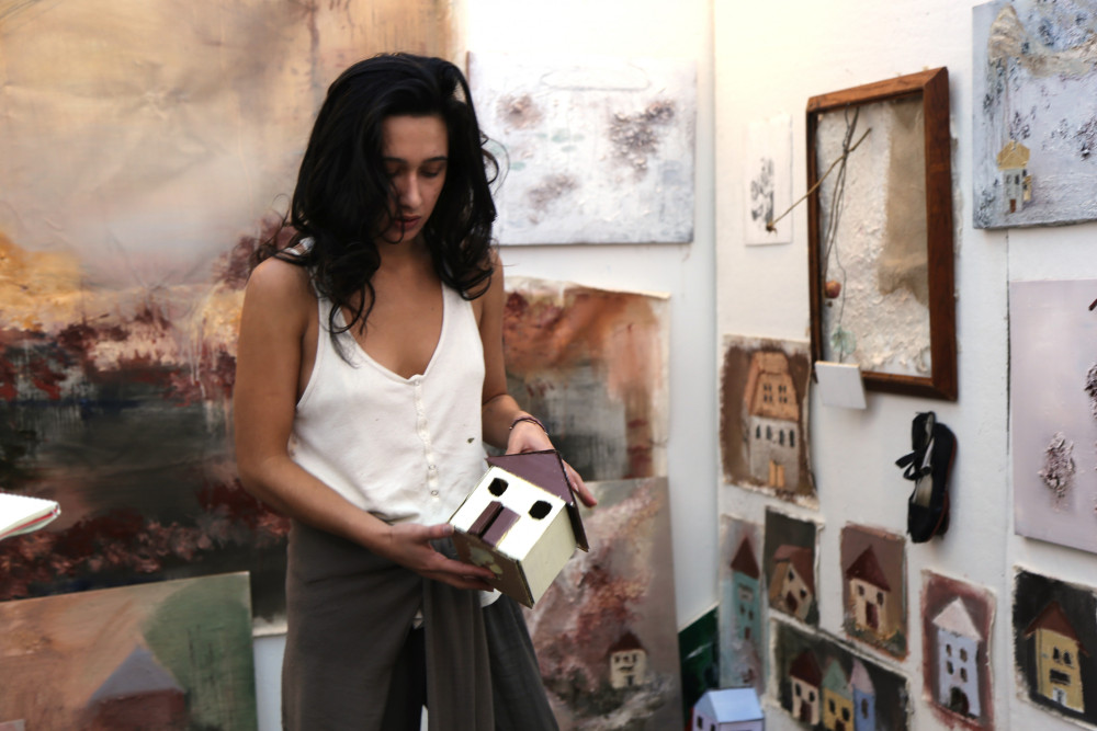 Valeria Orozco '18 holds a painted cardboard house in her painting studio