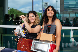 Two students hold items.