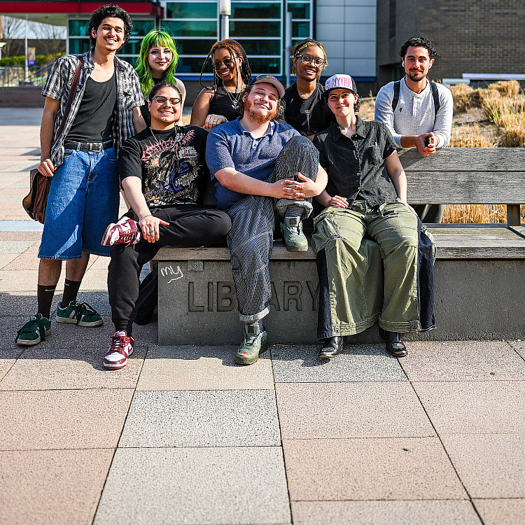 Group of students sits on a bench on SUNY Purchase campus