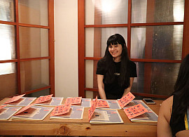 an image of Celine sitting at a table in front of zines at the School for Poetic Computation in New York.