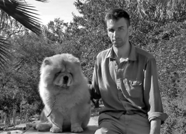 Black and white photo of Andrew Norman Wilson next to a big dog