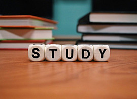 The word study spelled out in block letter across a table in front of a stack of books.