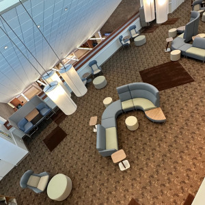 Aerial view of second floor reading room showing new sectional couches in light blue and sage green, two-person booth, and wing-back chai...