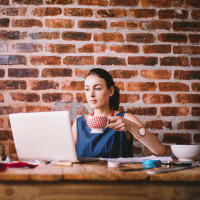 Young businesswoman working on laptop and drinking coffee