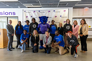 Group of students and administrators posing with school mascot