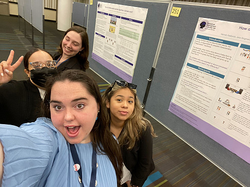 Students smile in front of a research poster.